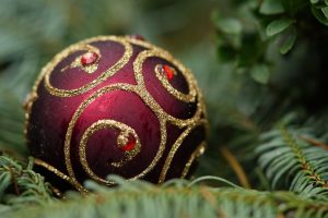 Red bauble with a gold pattern on it, sitting on a Christmas tree