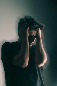 Young white male with his hands in his hair looking very angry or upset